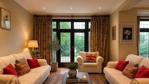 A living room with two sofas, a coffee table, and a large window with curtains. - Brook House (Stoke Poges)