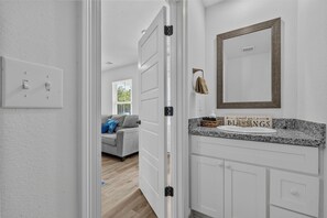 A hallway with a white door, a light switch, and a towel rack. - New 3BR Home- Less Than 1 Mile From The Beach (Gulfport)
