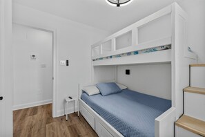 A room with a bunk bed, a small bedside table, and a door. - New 3BR Home- Less Than 1 Mile From The Beach (Gulfport)