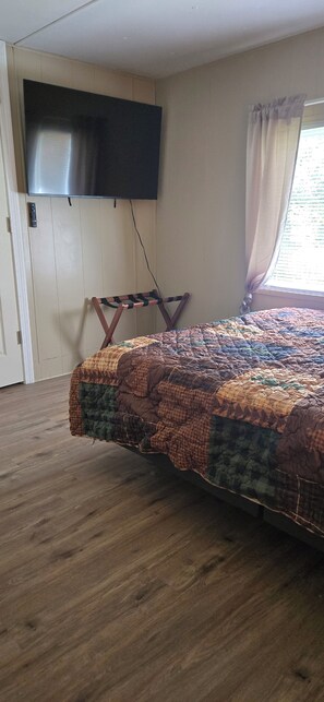 A bedroom with a bed, a television mounted on the wall, and a window with curtains.
