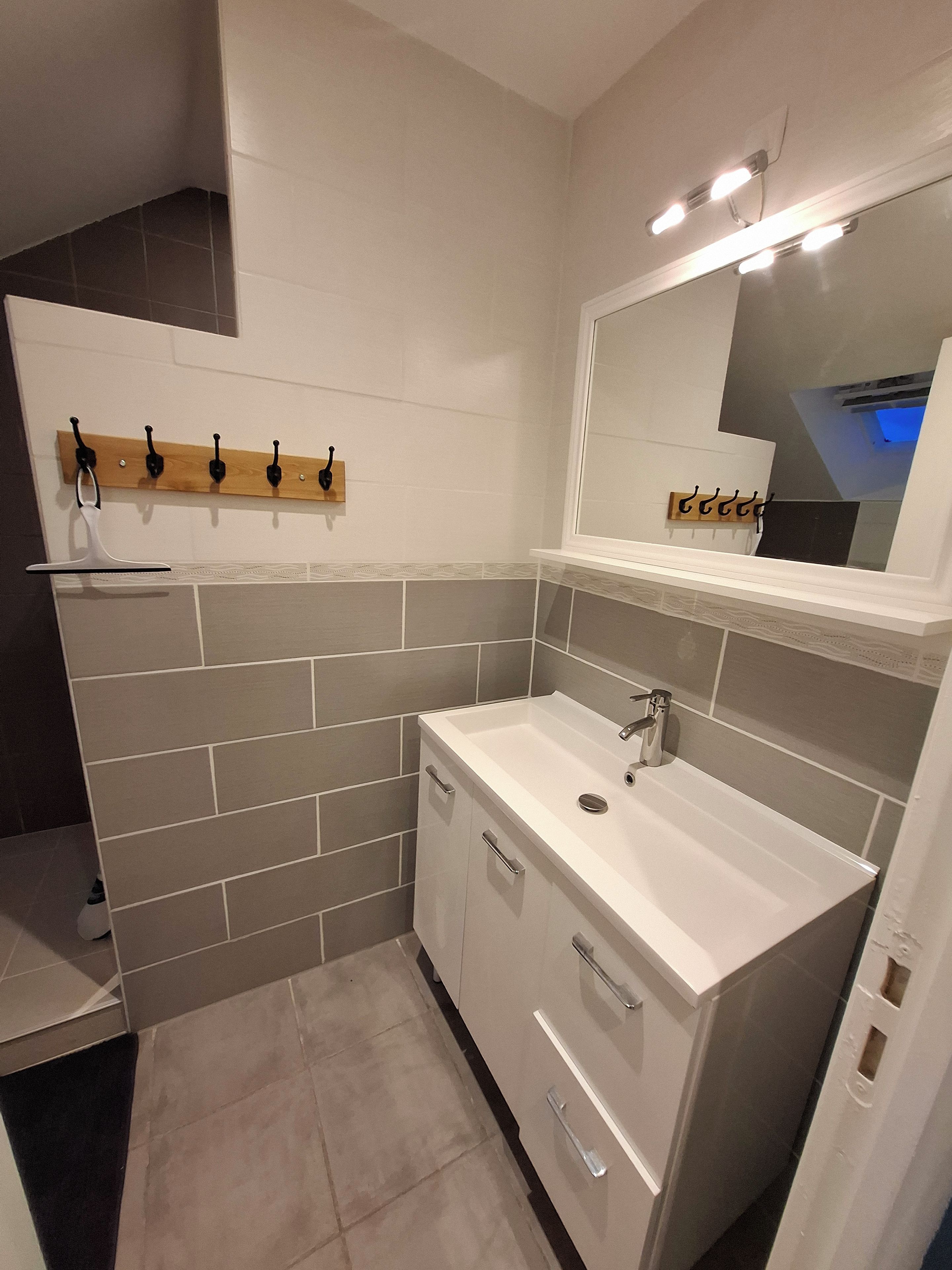 Casa de banho com lavatório branco, espelho e porta-toalhas.