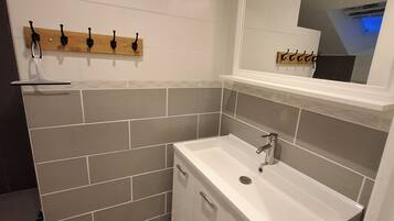 Casa de banho com lavatório branco, espelho e porta-toalhas.