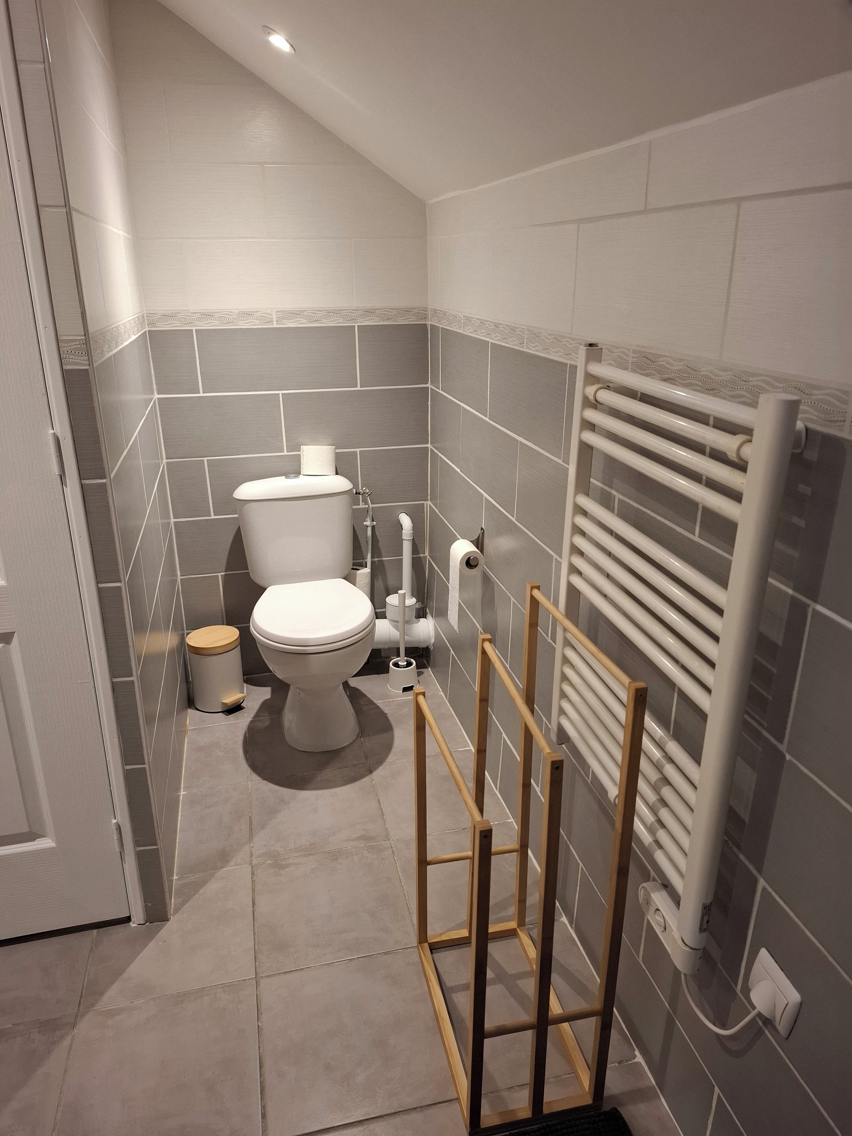 A bathroom with a toilet, a bidet, a radiator, and a wooden frame structure.