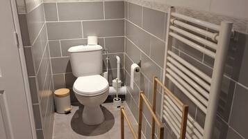A bathroom with a toilet, a bidet, a radiator, and a wooden frame structure.