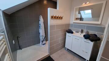 Un bagno moderno con doccia, un mobile lavabo con specchio e un portascopevoli.