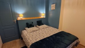 Un dormitorio con cama, lámparas de noche, cabecera de madera y una lámpara en el techo.