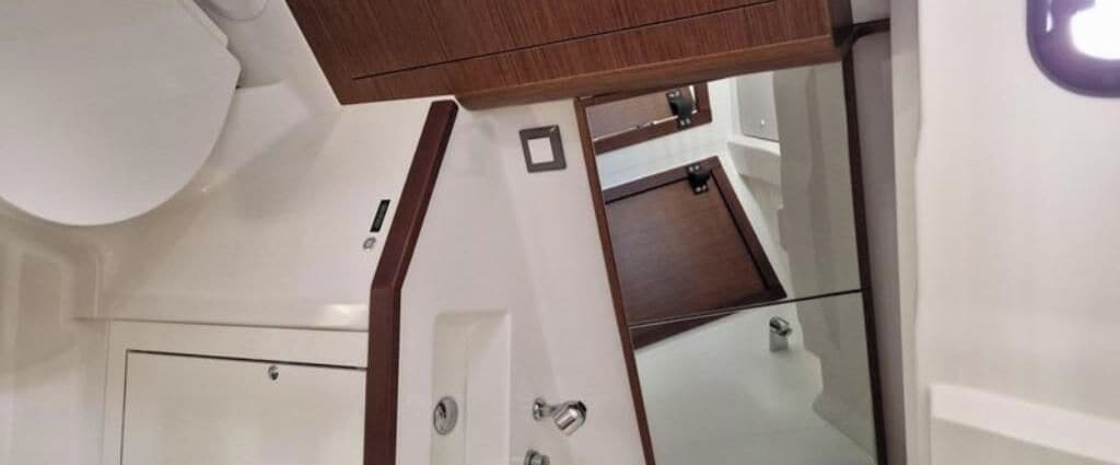 A bathroom with a white toilet, a wooden vanity, and a glass shower enclosure.