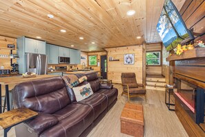 Un intérieur de chalet chaleureux avec un canapé en cuir, un coin repas et une cuisine.