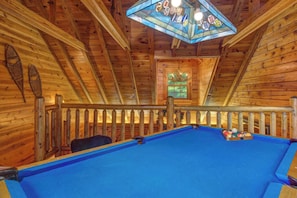 A pool table in a wooden room with a stained glass ceiling and a window with a view of greenery. - Welcome to LeConte Lookout, your perfect Sevierville escape designed for family (Sevierville)