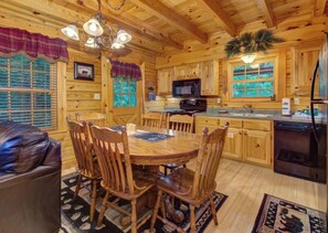 A wooden cabin interior with a dining table, chairs, a kitchen area, and a fireplace. - Welcome to LeConte Lookout, your perfect Sevierville escape designed for family (Sevierville)