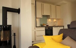A compact kitchen with white cabinets, a black stove, and a sink. - Villa Strandvogt App. Evening sun Baltic Sea (Boergerende-Rethwisch)
