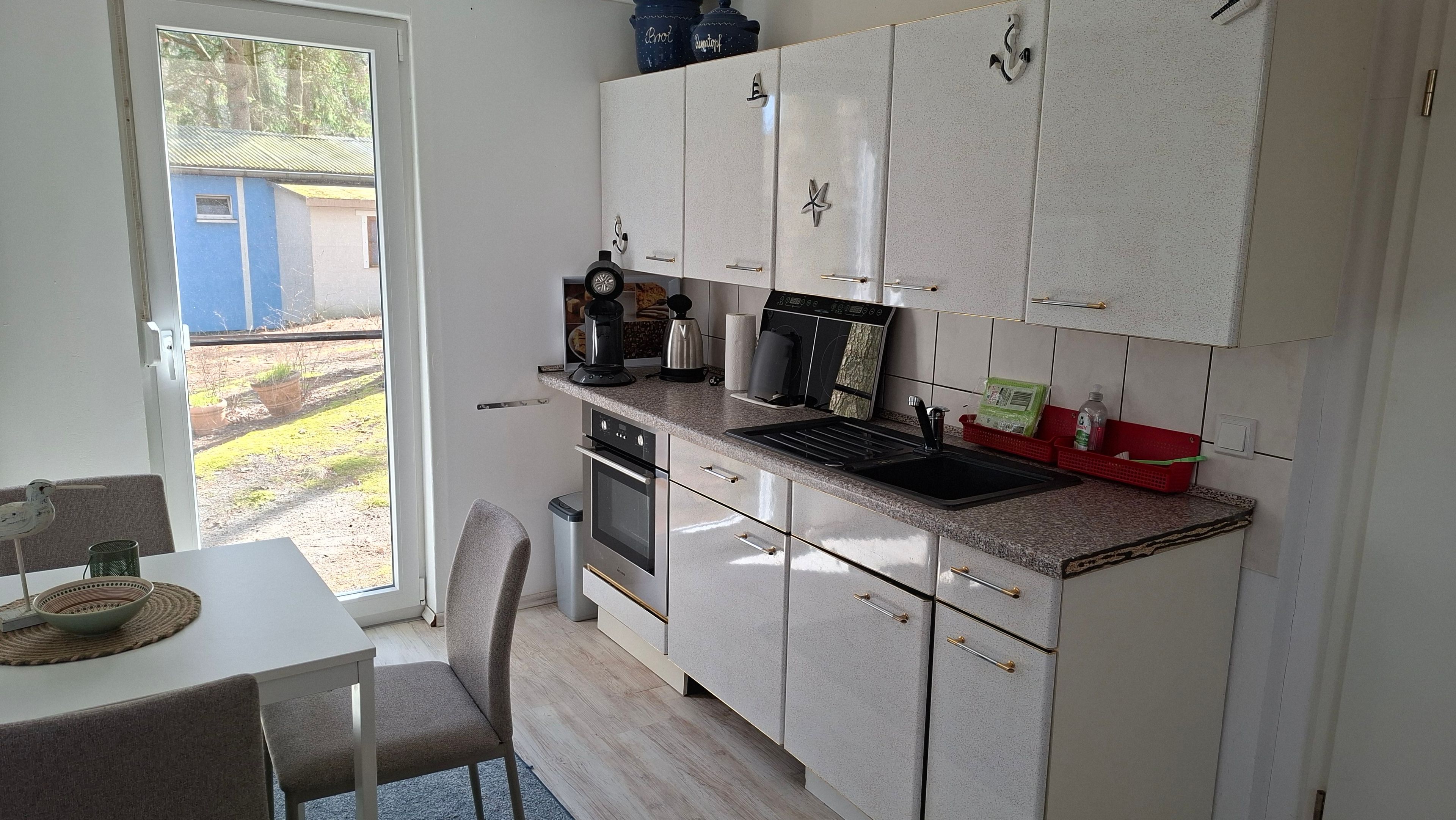 A compact kitchen with a built-in oven, a coffee maker, and a sink.