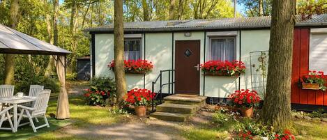 Une maison mobile dotée d’une véranda, d’un espace salon extérieur et de jardinières.