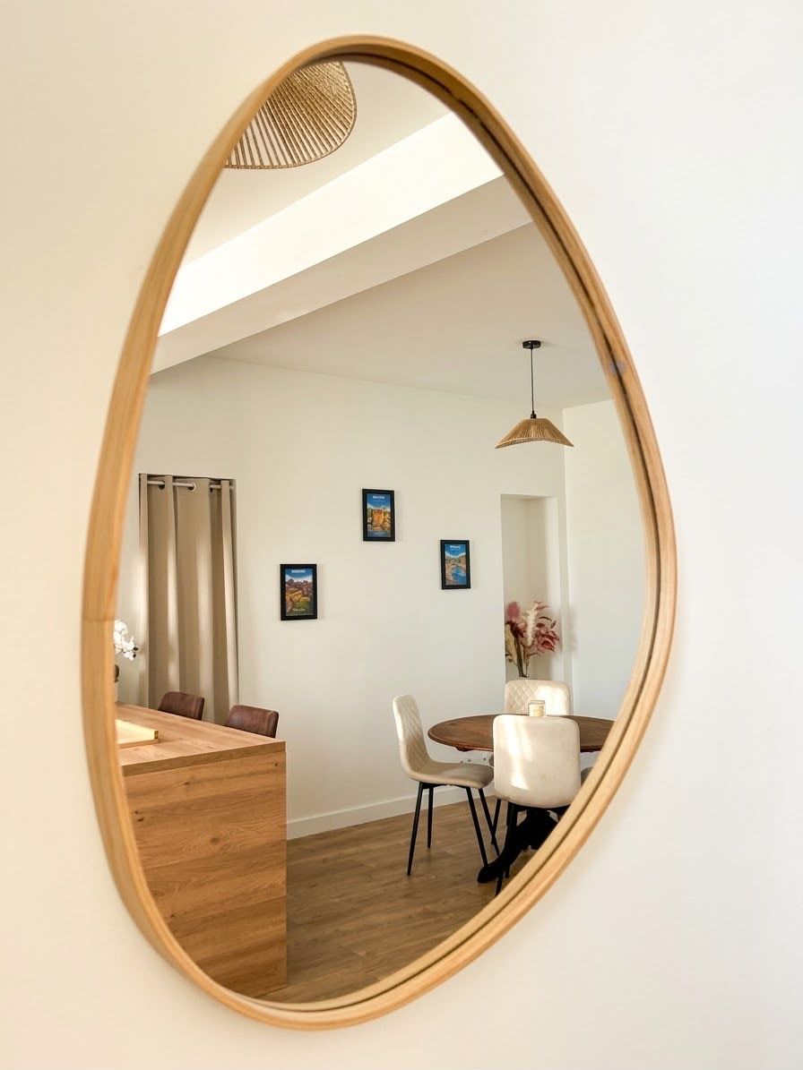 A dining area with a round table, chairs, and a mirror reflecting the space.