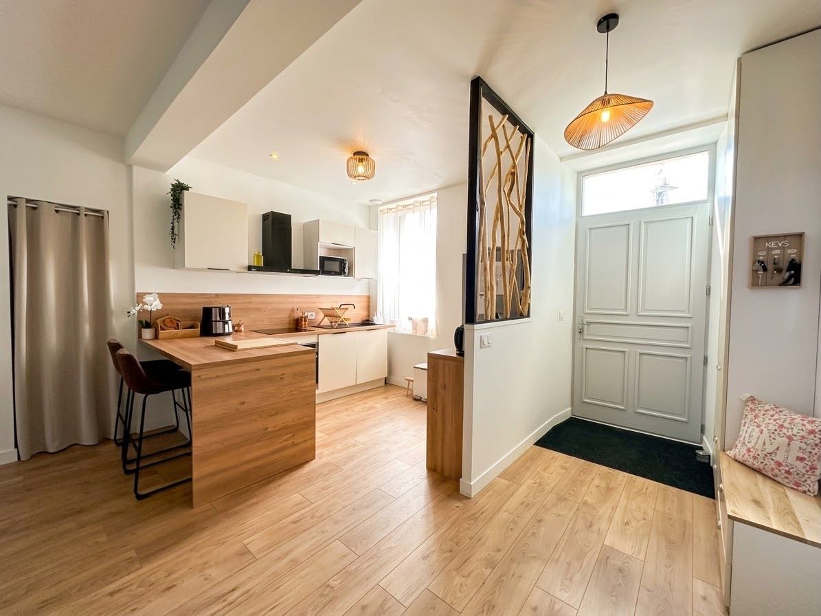 A modern kitchen with a wooden island, bar stools, and pendant lighting.