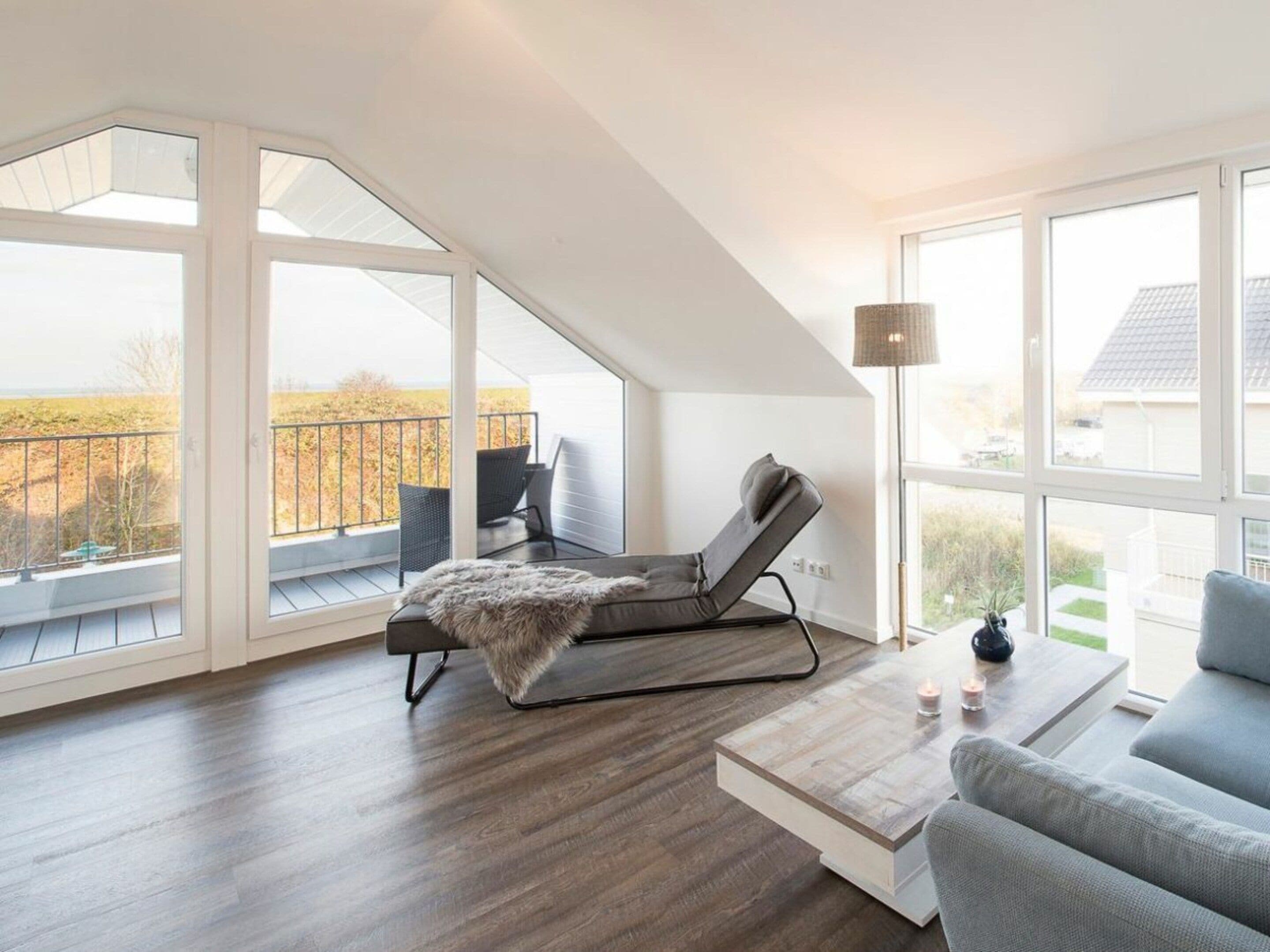 A modern living room with a large window, a lounge chair, a sofa, and a coffee table.
