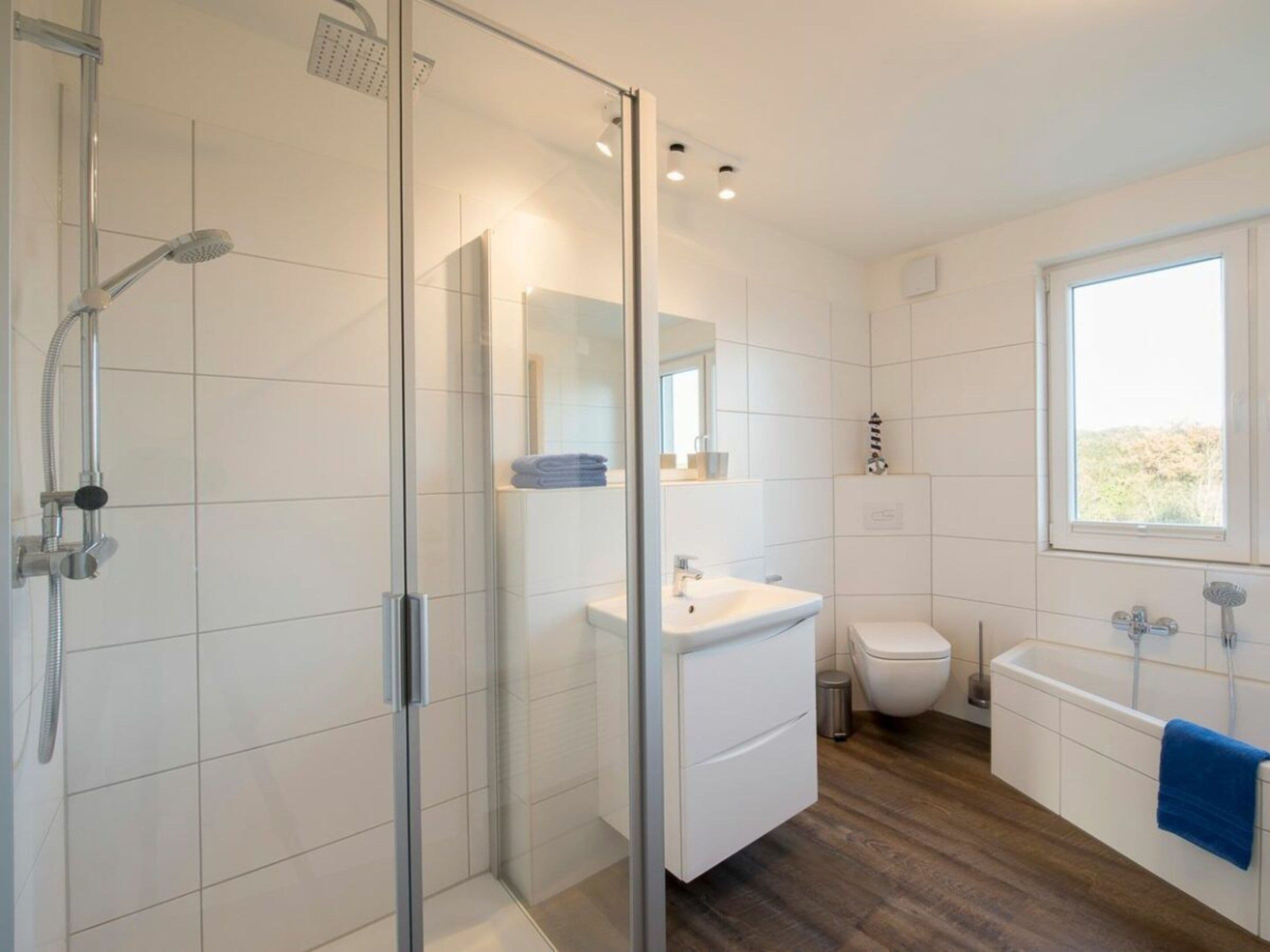 Ein modernes Badezimmer mit Duschkabine aus Glas, einem weißen Waschbecken, einer Toilette und einer Badewanne.
