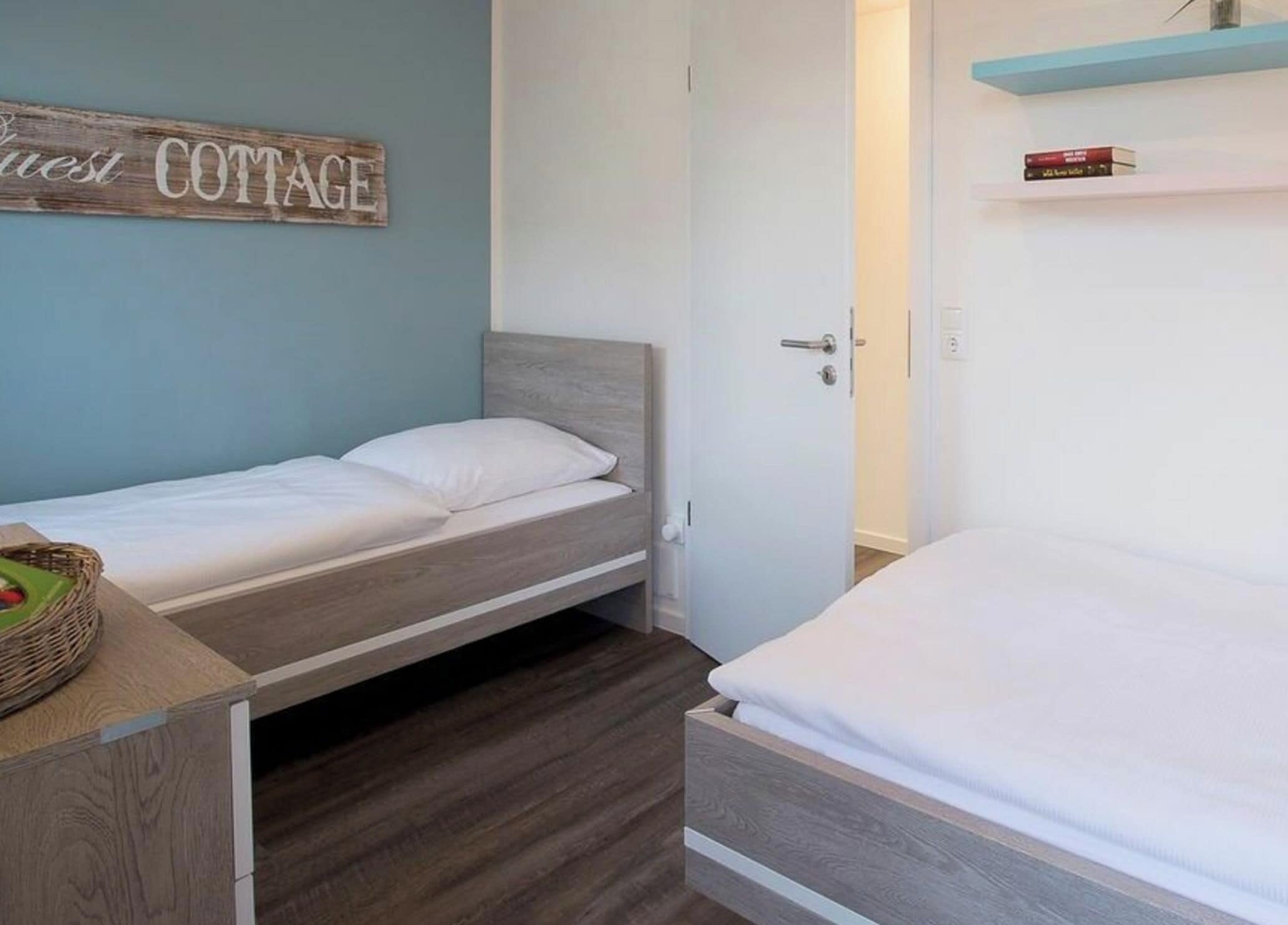 A single bed with a wooden headboard in a room with a light blue wall and a wooden floor.