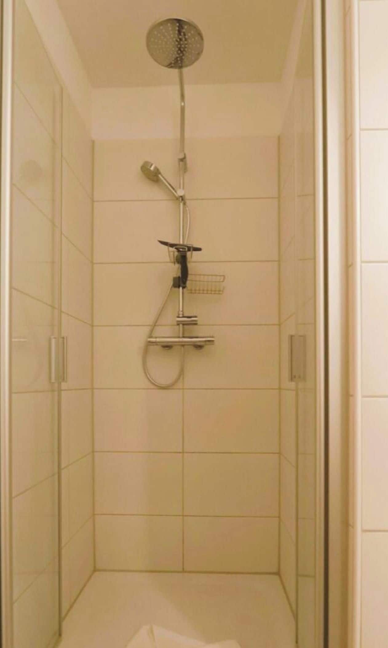 Eine Dusche mit Duschbrause und Wandarmatur.
