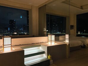 Ein modernes Hotelzimmer mit Blick auf die Stadt, ausgestattet mit einem Bett, einer Sitzecke und einer kleinen Treppe.