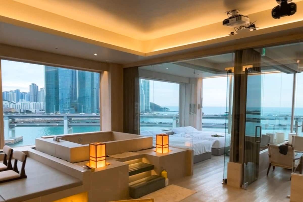Ein modernes Hotelzimmer mit Blick auf die Stadt, inklusive Balkon und einer Sitzecke mit Tisch und Stühlen.