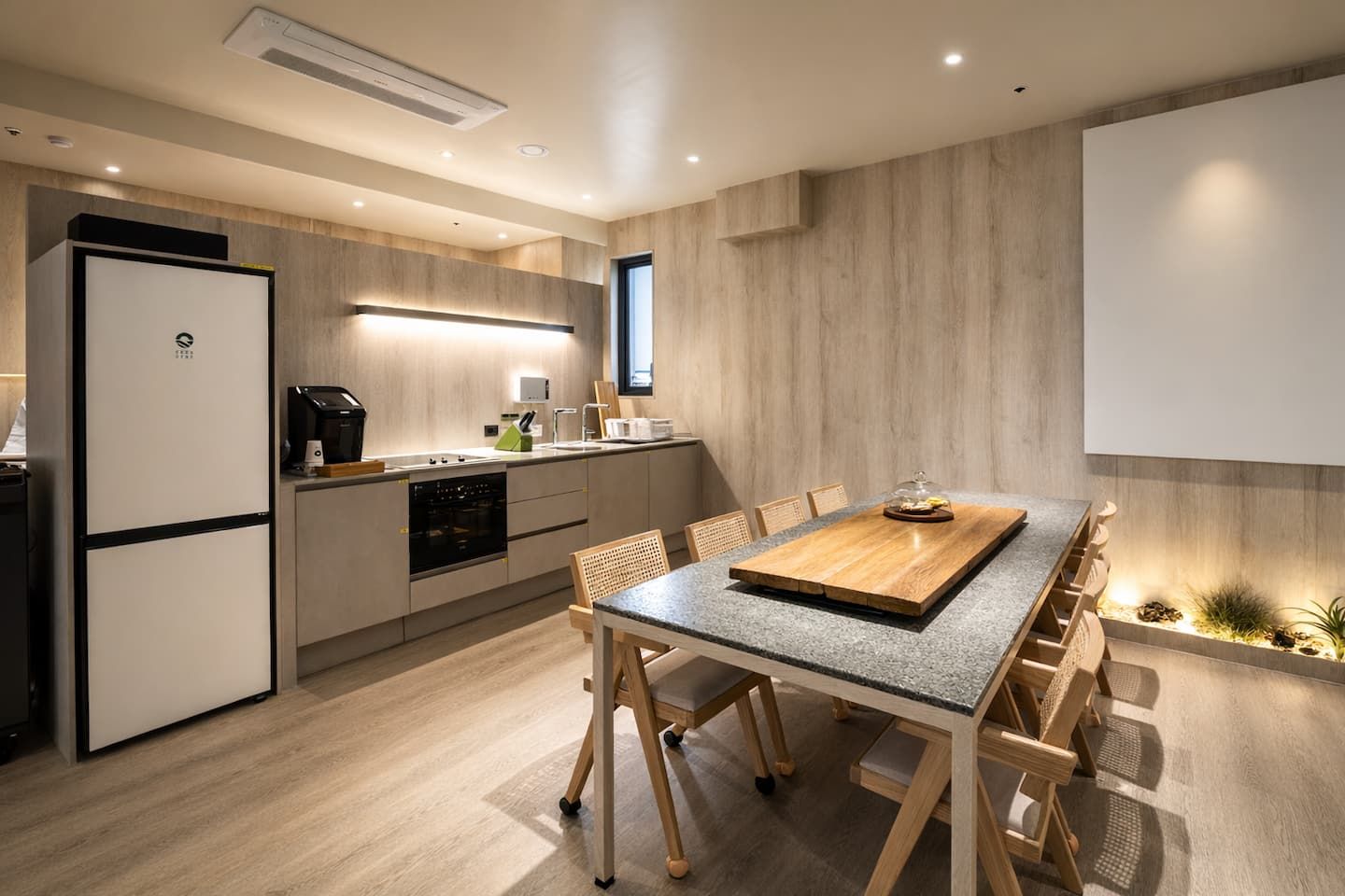 Eine moderne Küche mit Einbauofen, Kühlschrank und Essbereich mit Holztisch und Stühlen.