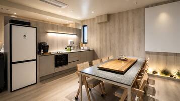 Eine moderne Küche mit Einbauofen, Kühlschrank und Essbereich mit Holztisch und Stühlen.