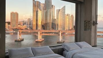 Ein Hotelzimmer mit zwei Betten und einem großen Fenster mit Blick auf die Stadt.