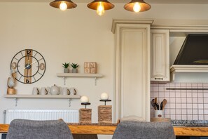 A kitchen with a white cabinet, a clock, and a shelf with decorative items. - Villa Konstantinos in Heraklion (Heraklion)