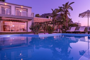 A modern hotel with a pool, outdoor seating, and tropical plants. - Villa Konstantinos in Heraklion (Heraklion)