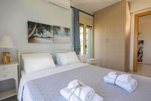A bedroom with a bed, a nightstand, a dresser, and a window with curtains. - Villa Konstantinos in Heraklion (Heraklion)
