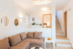 Ein Wohnzimmer mit einem braunen Ecksofa, einem weißen Couchtisch und einer Treppe, die zu einer oberen Etage führt.