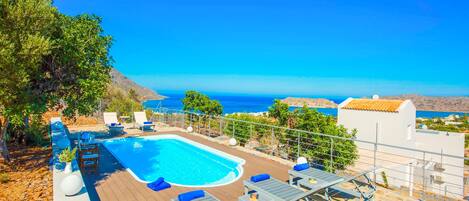 A swimming pool with lounge chairs and a view of the sea.