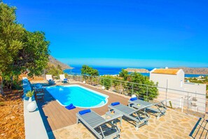 Ein Swimmingpool mit Liegestühlen und Blick auf das Meer.