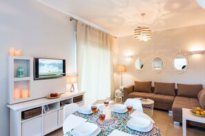 Ein modernes Wohnzimmer mit Essbereich, Fernseher und einer Couch.