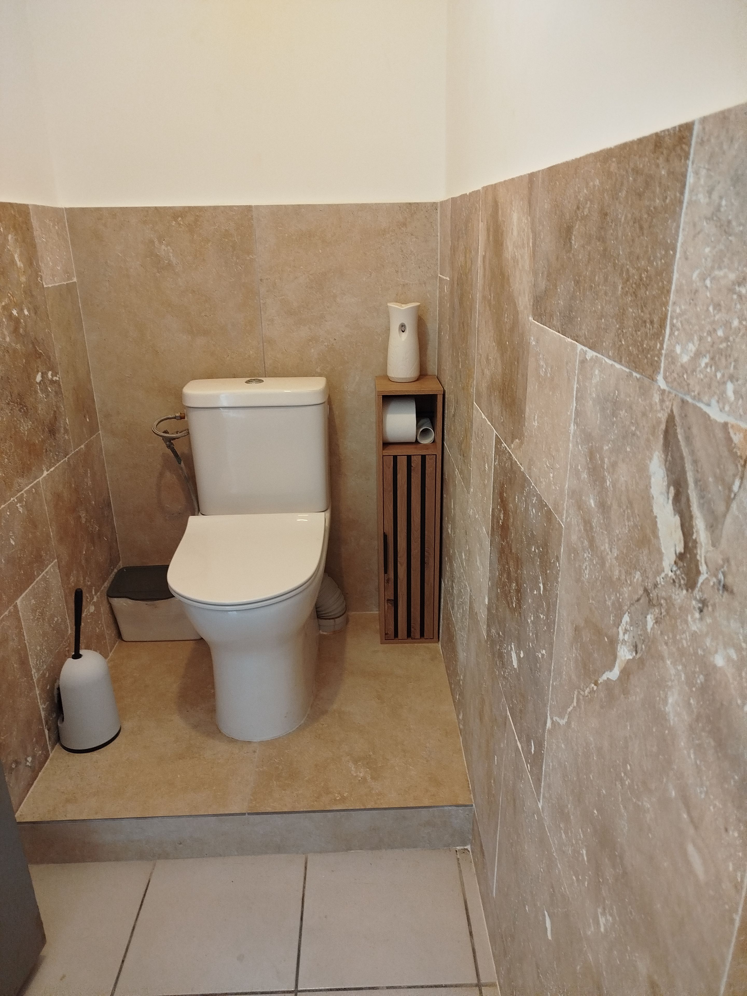 Ein Badezimmer mit Toilette, Toilettenbürste und Toilettenpapierhalter.