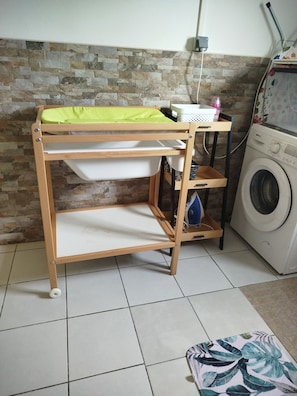 Een stapelbed met een wasruimte, een wasmachine en een betegelde vloer.