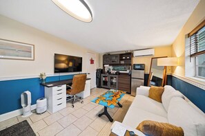 Een knus woongedeelte met een kitchenette, een bank, een bureau en een televisie.