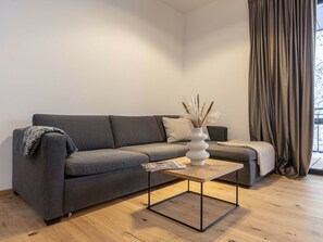 A modern living room with a grey sofa, a wooden coffee table, and a vase with dried plants. - Holiday Apartment & Infinity Pool (Sankt Martin am Tennengebirge)