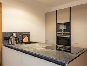 A modern kitchen with a black countertop, stainless steel appliances, and a built-in oven. - Holiday Apartment & Infinity Pool (Sankt Martin am Tennengebirge)
