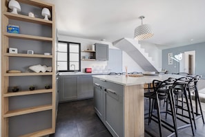 Eine moderne Küche mit einer zentralen Kochinsel, Barhocker und einer Treppe zu einer weiteren Ebene.
