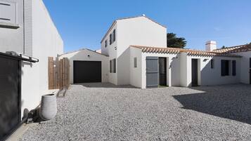 Ein Wohnhaus mit Schotterauffahrt, Garage und kleinem Eingangstor.