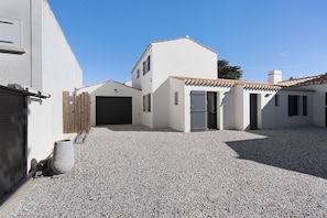 Ein Wohnhaus mit Schotterauffahrt, Garage und kleinem Eingangstor.