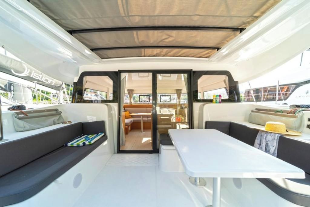 A yacht interior with a dining area, seating, and a view through the glass doors.