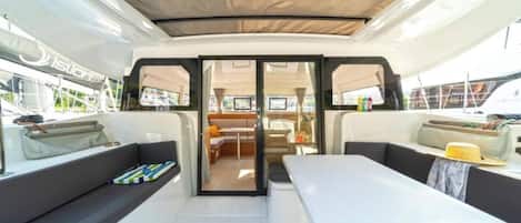 A yacht interior with a dining area, seating, and a view through the glass doors.