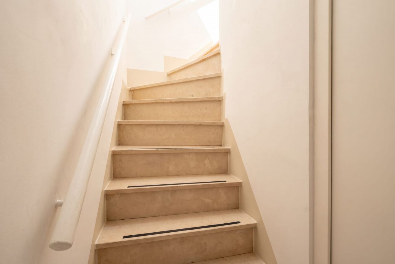 Een trap met een leuning en een lichtgekleurde muur.