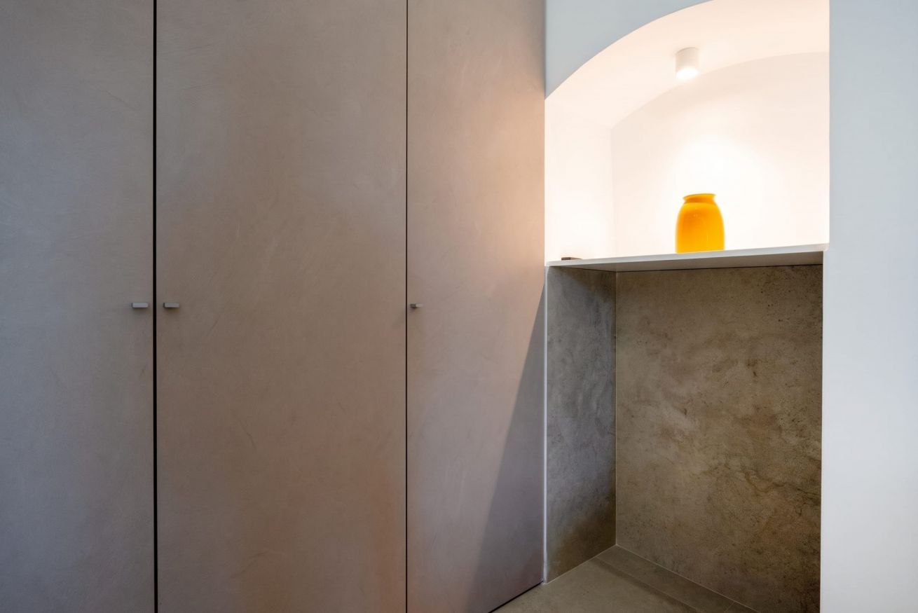 Un coin de pièce avec un mur blanc, une porte beige et une étagère sur laquelle se trouve un objet jaune.