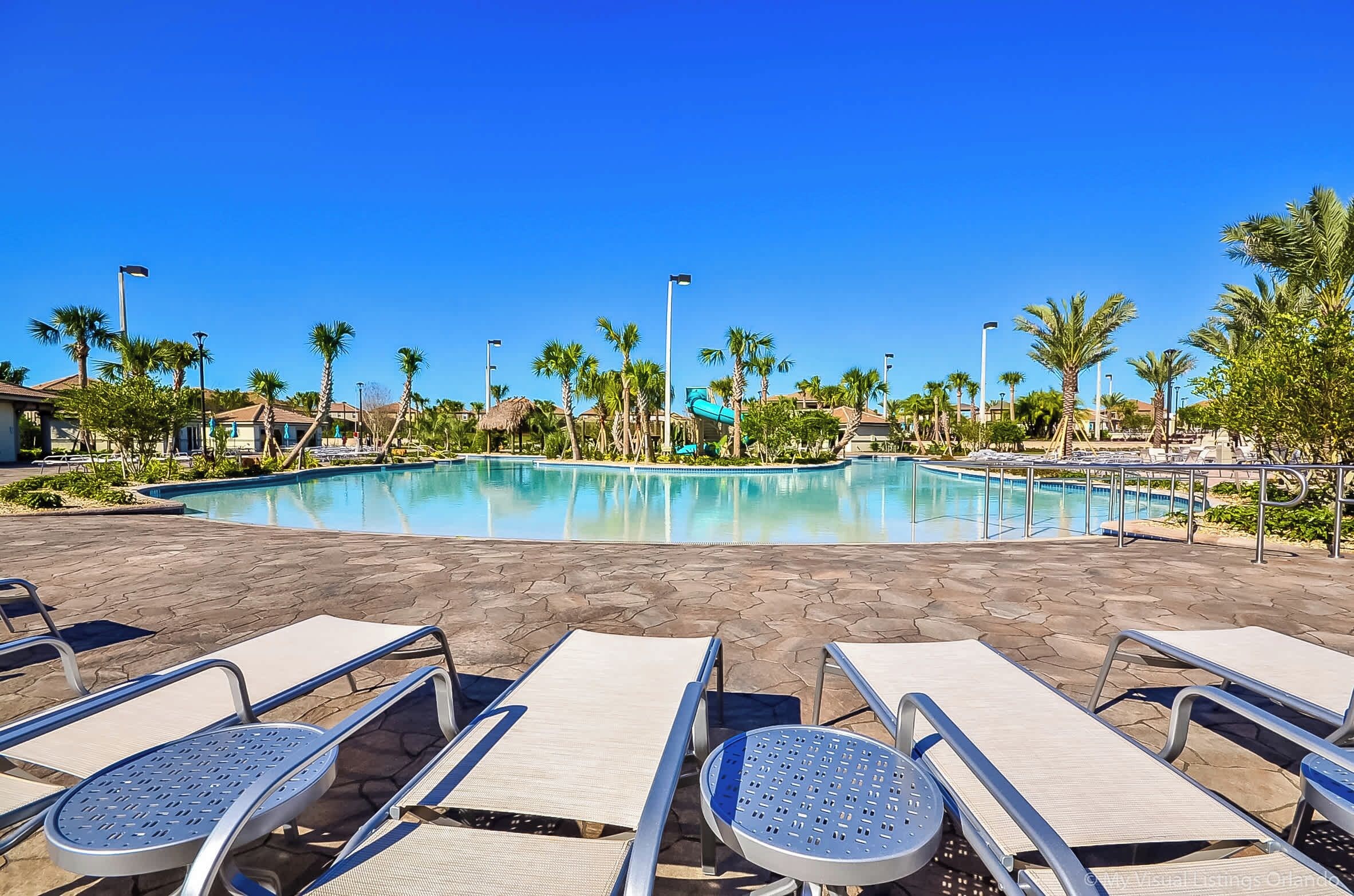 A resort pool area with lounge chairs and a clear blue sky.
