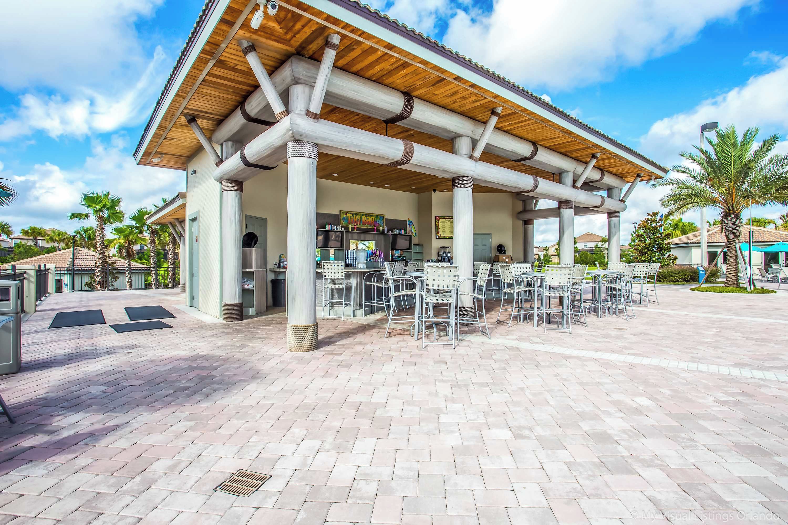 A covered outdoor seating area with tables and chairs, a kiosk, and a sign that reads "TIKBIN".