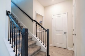 A staircase with black railings leading to a white door. - ⭐⭐⭐⭐⭐ Price Drop! OCT-NOV! Dreamy 5BR • Cozy Home • Themed Rooms • Hot Tub! (Davenport)